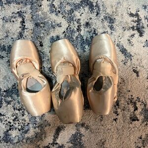 Three pairs of used pointe shoes.